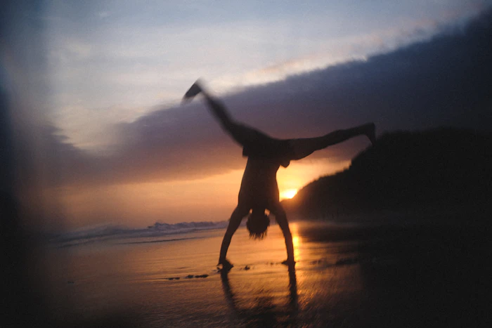 Traveler cartwheeling on the beach at sunset