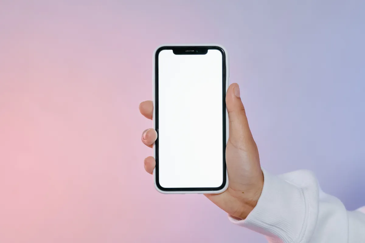 Mano sosteniendo un smartphone con la pantalla en blanco